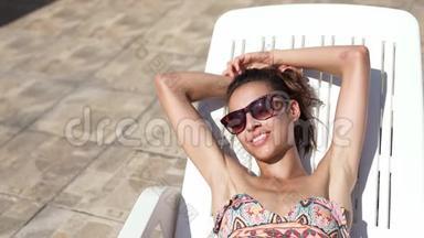 高瞻远瞩的美丽身材白种人比基尼女士，身体健康，腹部平坦，躺在桌椅和日光浴